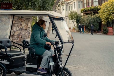 Persoană în vârstă zâmbind în timp ce pedalează o tricicletă electrică