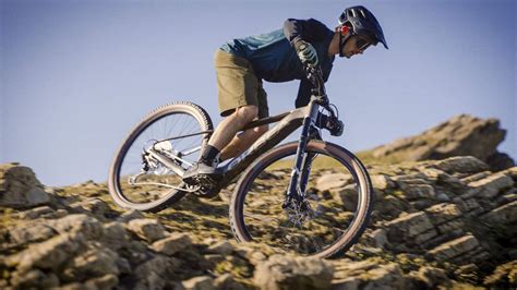 Ciclista su mountain bike con parafanghi che affronta un percorso fangoso