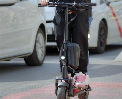 Un pendolare sorridente che guida uno scooter elettrico Apollo Light in una città moderna.