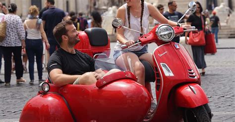 Vespa con sidecar in un contesto urbano storico