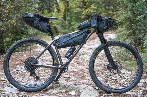 Ciclista con borse da bikepacking su una strada panoramica