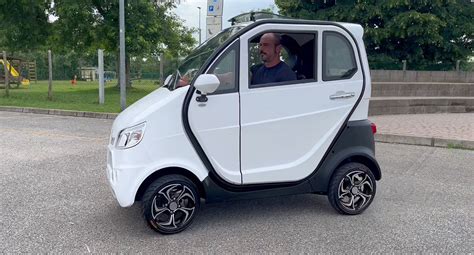 Scooter elettrico cabinato a quattro ruote in un contesto urbano