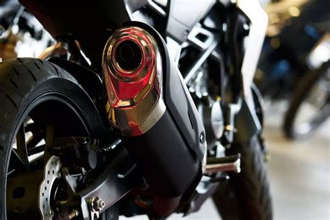 Primo piano di un tecnico che ispeziona un terminale di scarico di moto