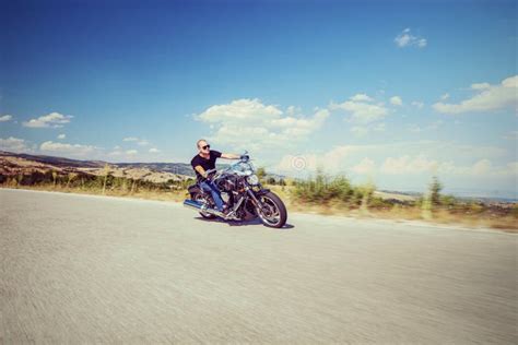 Motociclista su una moto street scrambler che guida su una strada di campagna
