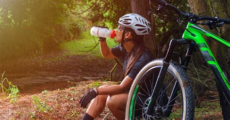 Ciclista che beve da una borraccia durante una discesa in mountain bike