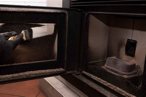 Persona che pulisce una stufa a pellet con un aspirapolvere